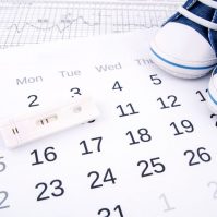 Positive pregnancy test on calendar and baby shoes
